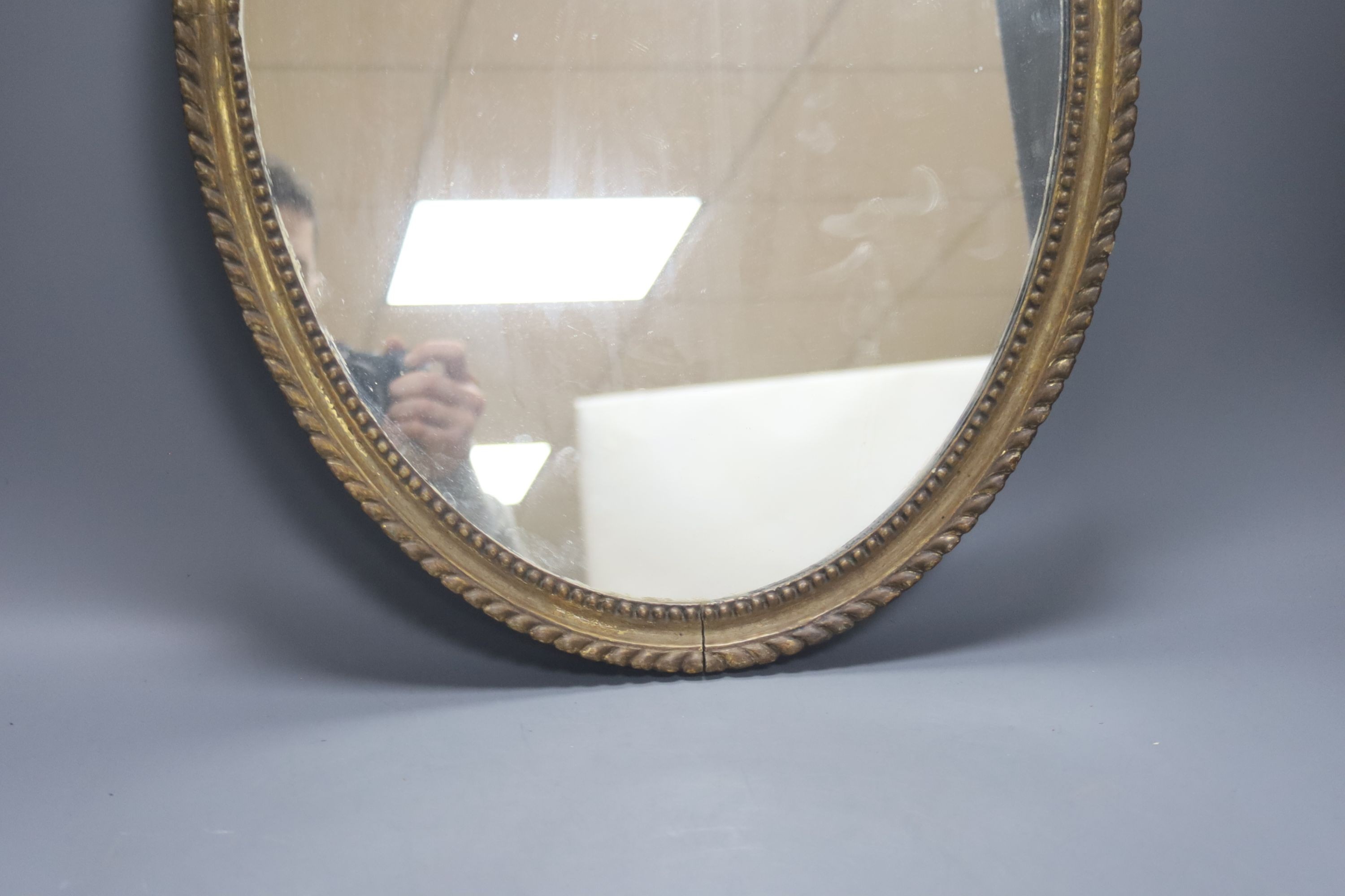 An oval gilt framed wall mirror, 55.5 cm high